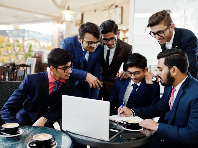 Collaborative process of indian business mans during brainstorming meeting in office.Diverse team of young people dressed in suits cooperating on developing common project.